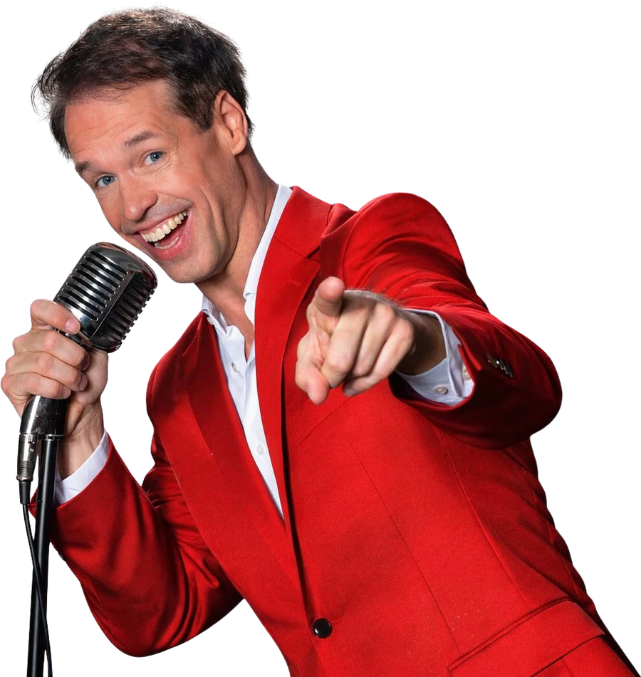 Dave van de Dam zingt met de microfoon, wijzend naar de camera
